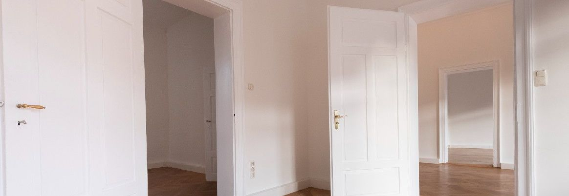 Leere Wohnung mit weißen Türen und Parkettboden